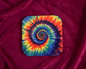 Colorful tie-dye spiral design on a square coaster against a beige background